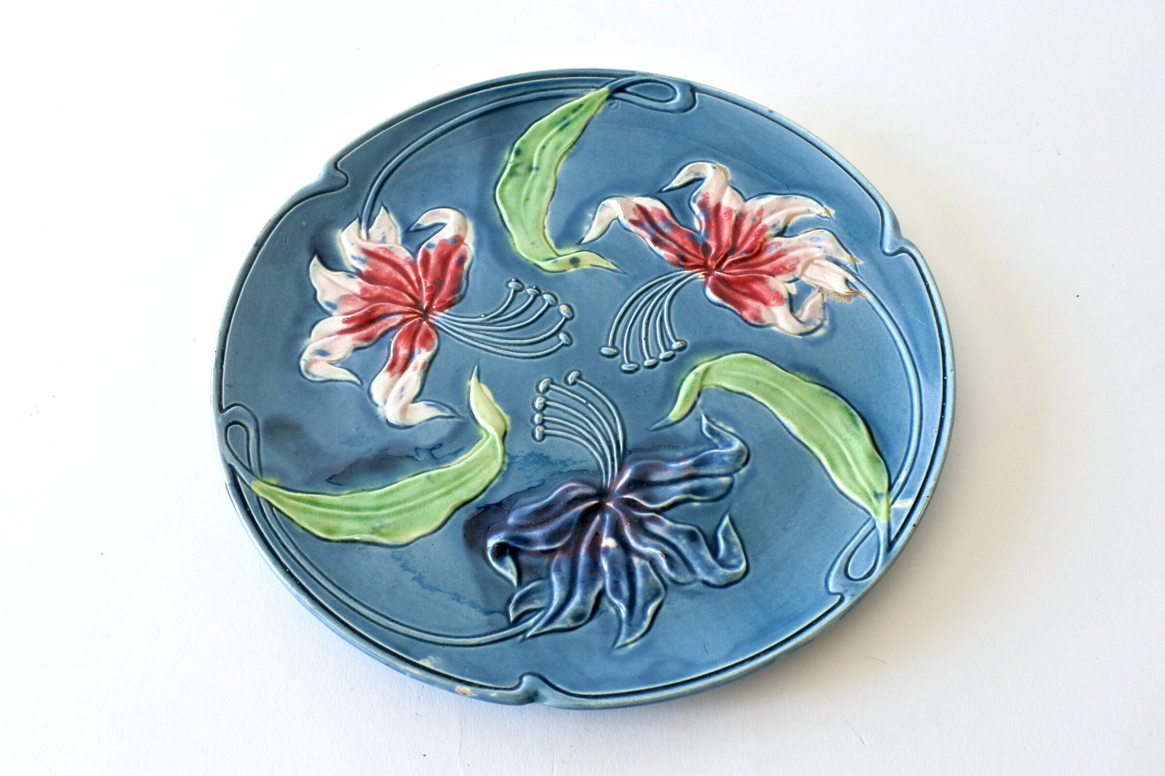 Piatto in ceramica barbotine con fiori di giglio rosso bianco e blu
